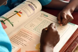Child writing in a Quranic Tarbiyah madrasah curriculum book